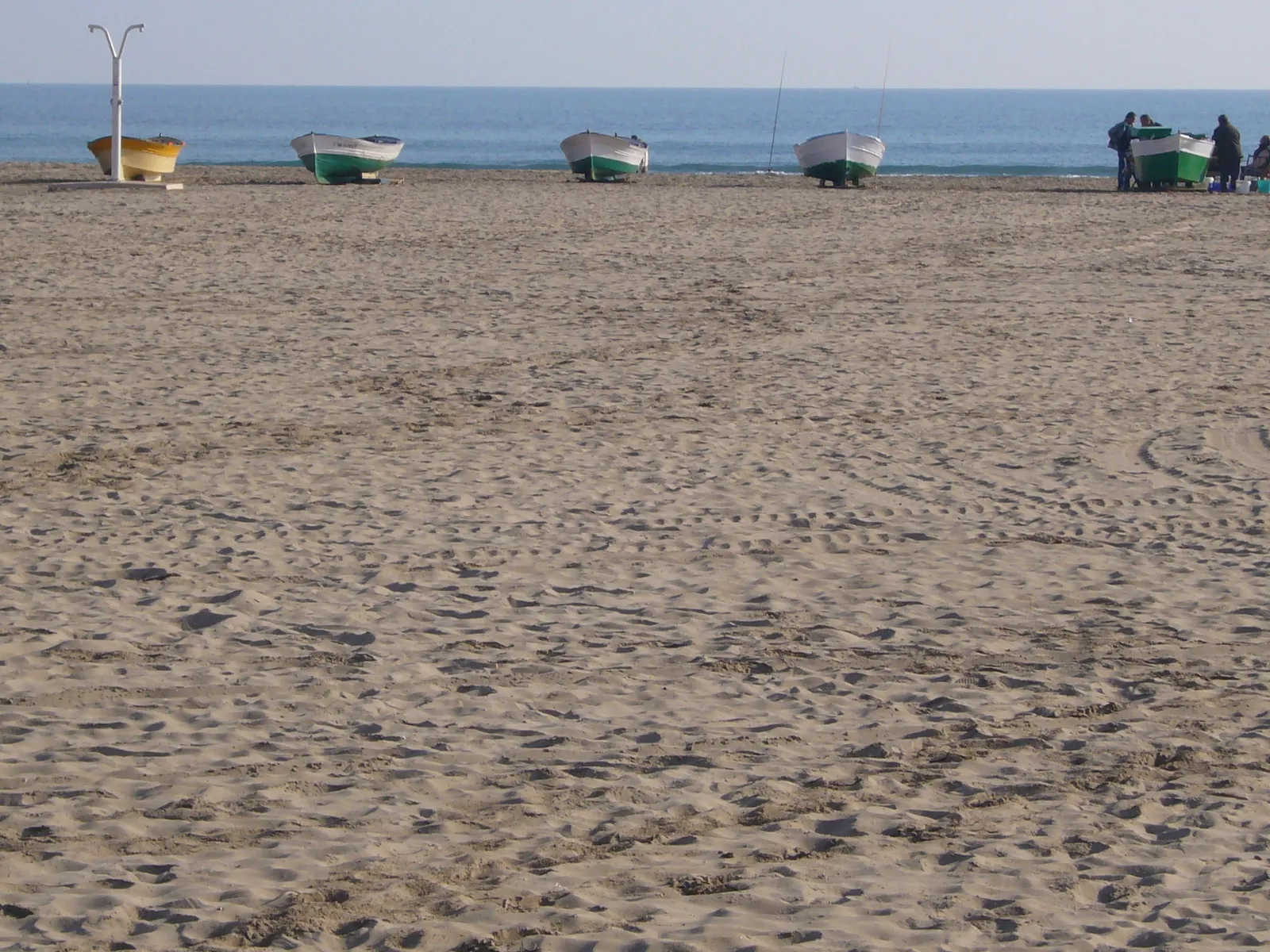 Sand der Platja de la Malva-rosa mit kleinen Fischerbooten am Strand.