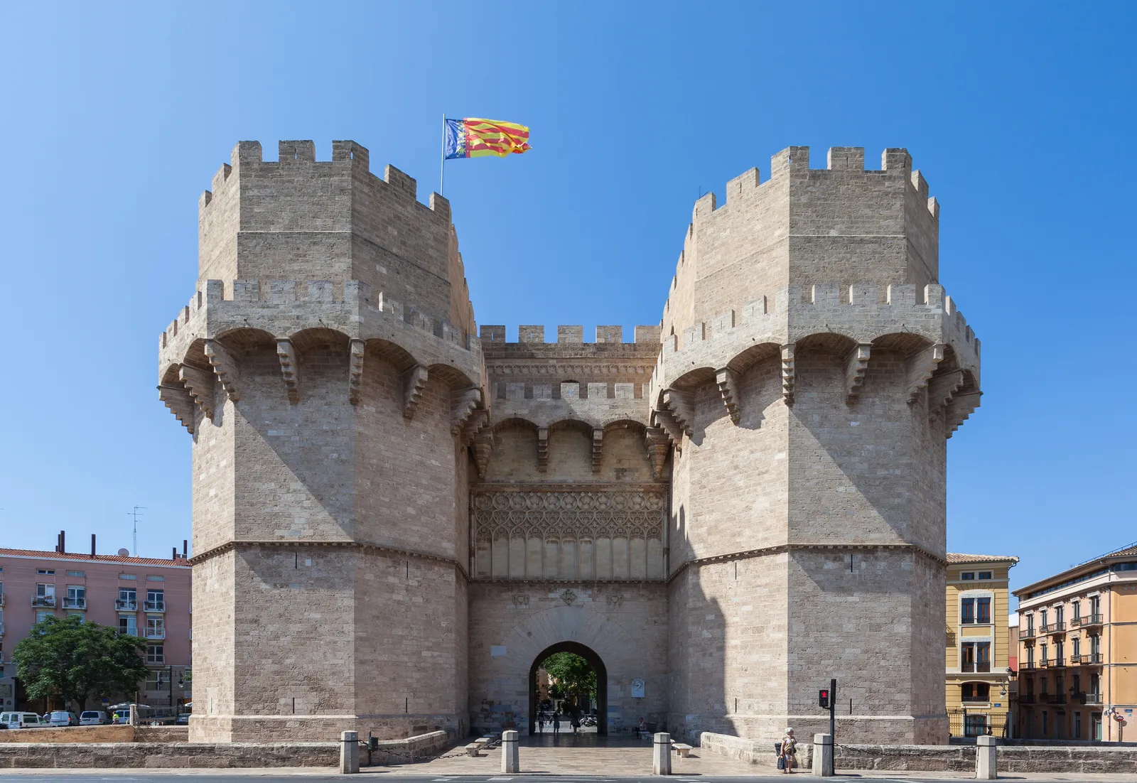 Die zwei zinnenbewehrten Steintürme des Stadttors Torres de Serranos unter blauem Himmel.