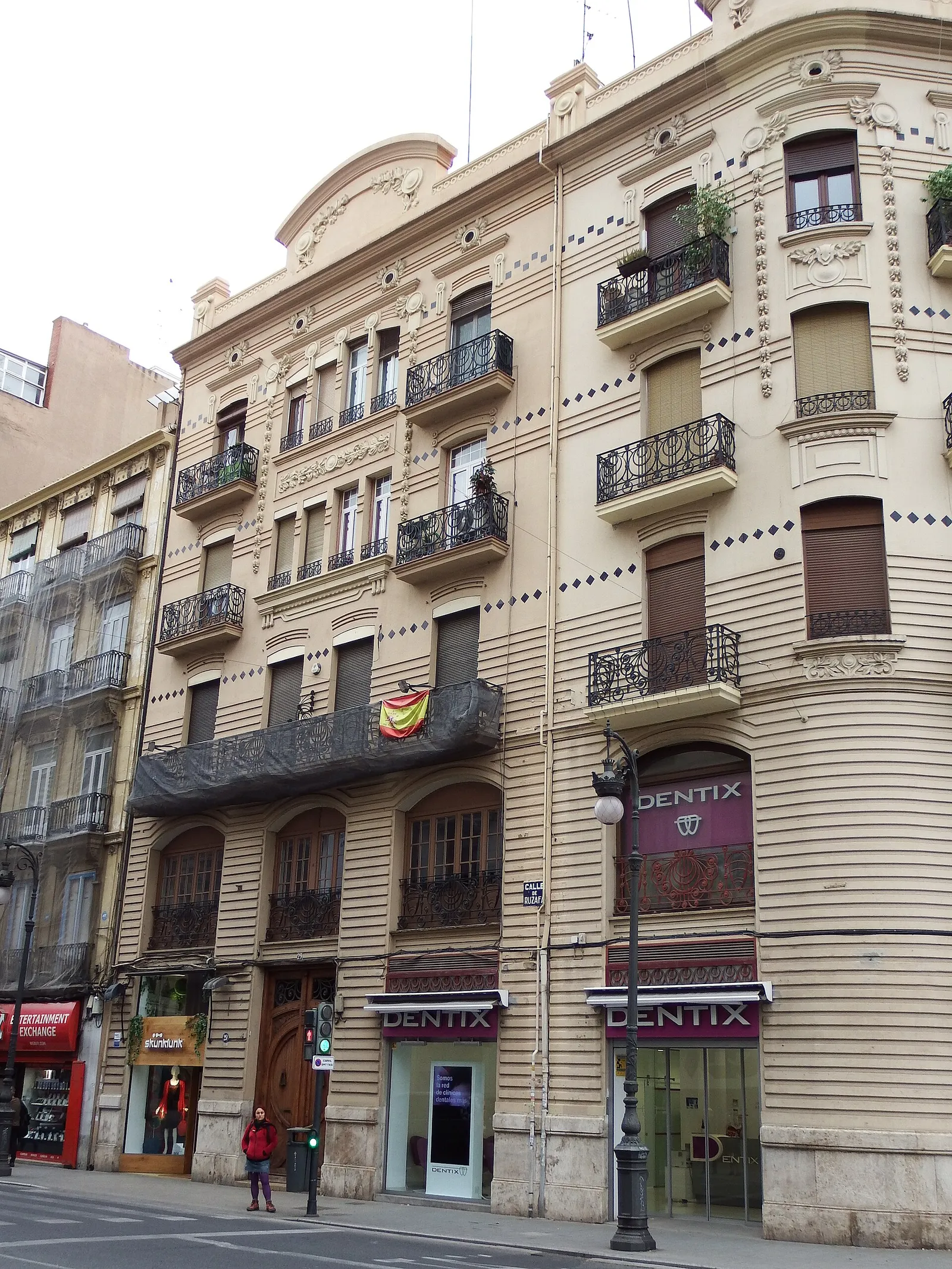 Hohes Wohnhaus mit Balkonen und Geschäften im Erdgeschoss an einer Straße in Valencia