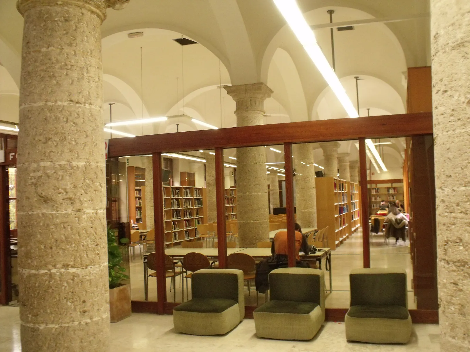 Lesesaal einer städtischen Bibliothek in Valencia mit Sesseln und Regalen hinter Glas.