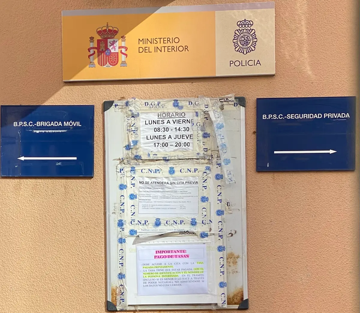 Ministry of the Interior police sign above two blue direction boards with notices between them