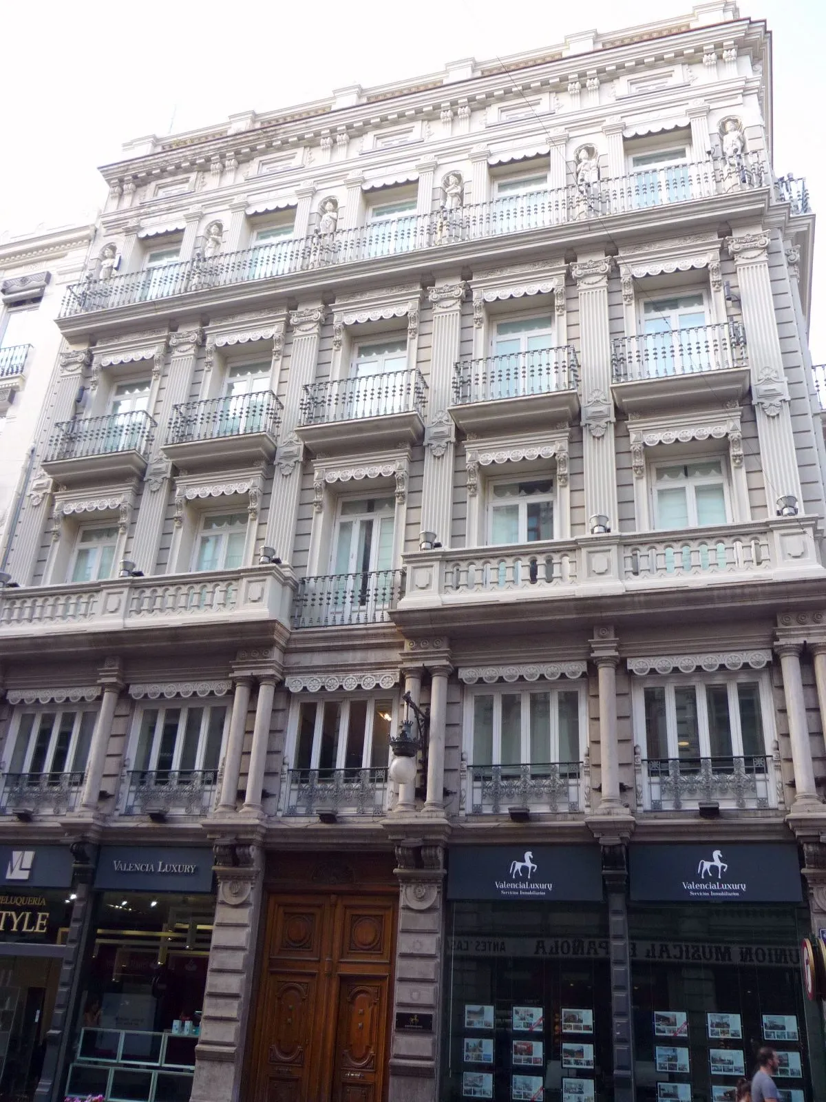 Reich verzierte Steinfassade mit Balkonen und Markisen an einer Straße im Zentrum von Valencia