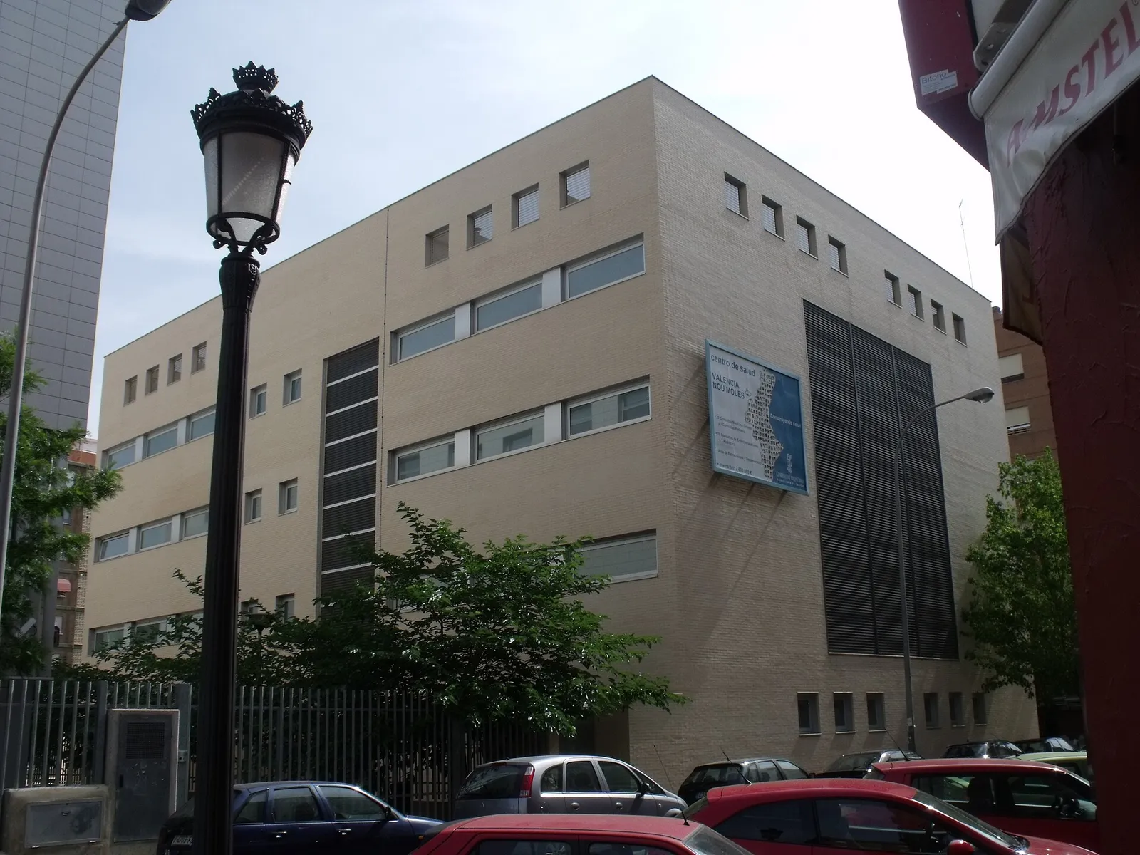Beiges Gesundheitszentrum an einer Stadtstraße mit Straßenlaterne und parkenden Autos