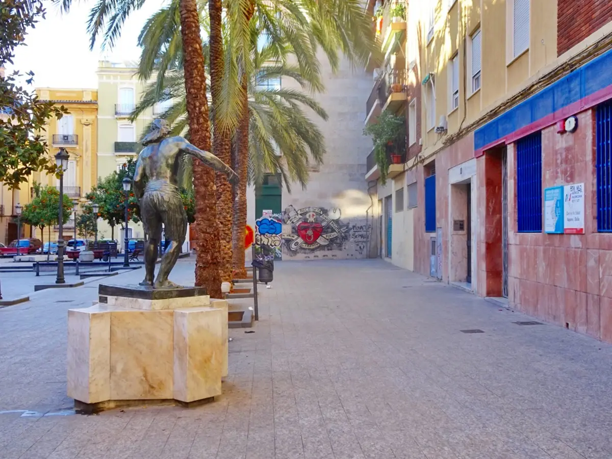 Kleiner Platz mit einer Bronzestatue und dem Gebäude des Gesundheitszentrums rechts