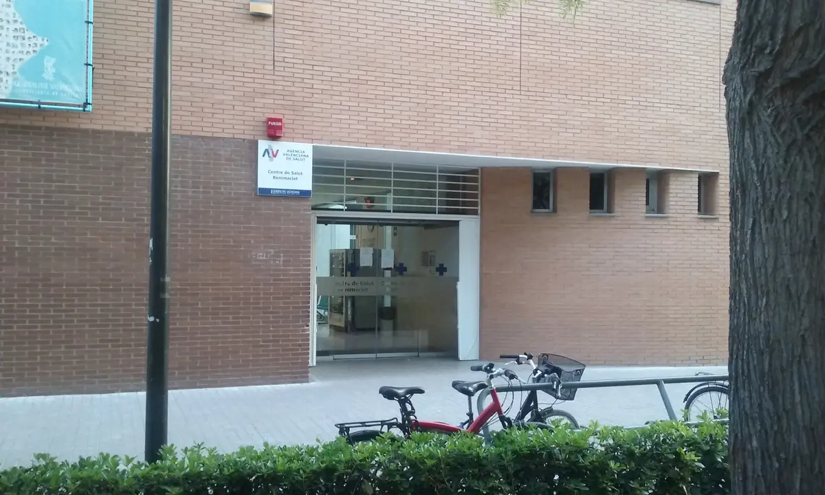 Eingang eines Centro de salud aus Backstein mit Glastüren und einem davor abgestellten Fahrrad