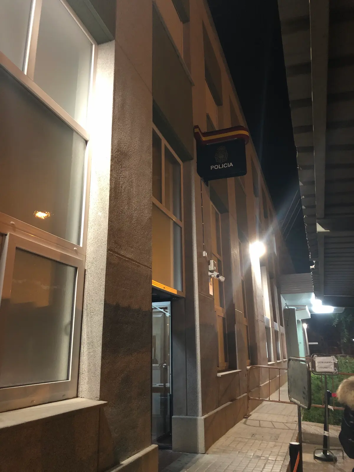 Fassade einer Polizeidienststelle in Valencia bei Nacht, mit einem Polizeischild über dem Eingang.