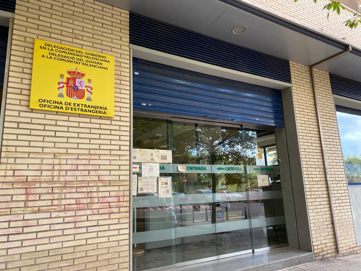 Eingang der Oficina de Extranjería in Valencia mit einem gelben Behördenschild neben der Glastür.