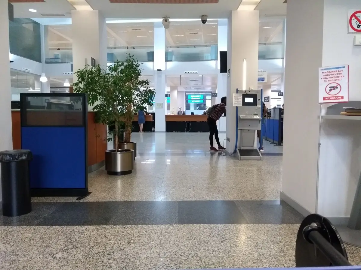 Öffentliche Halle in einem Finanzamt mit Serviceschalter, einer Pflanze und einem Boden aus gesprenkeltem Stein.
