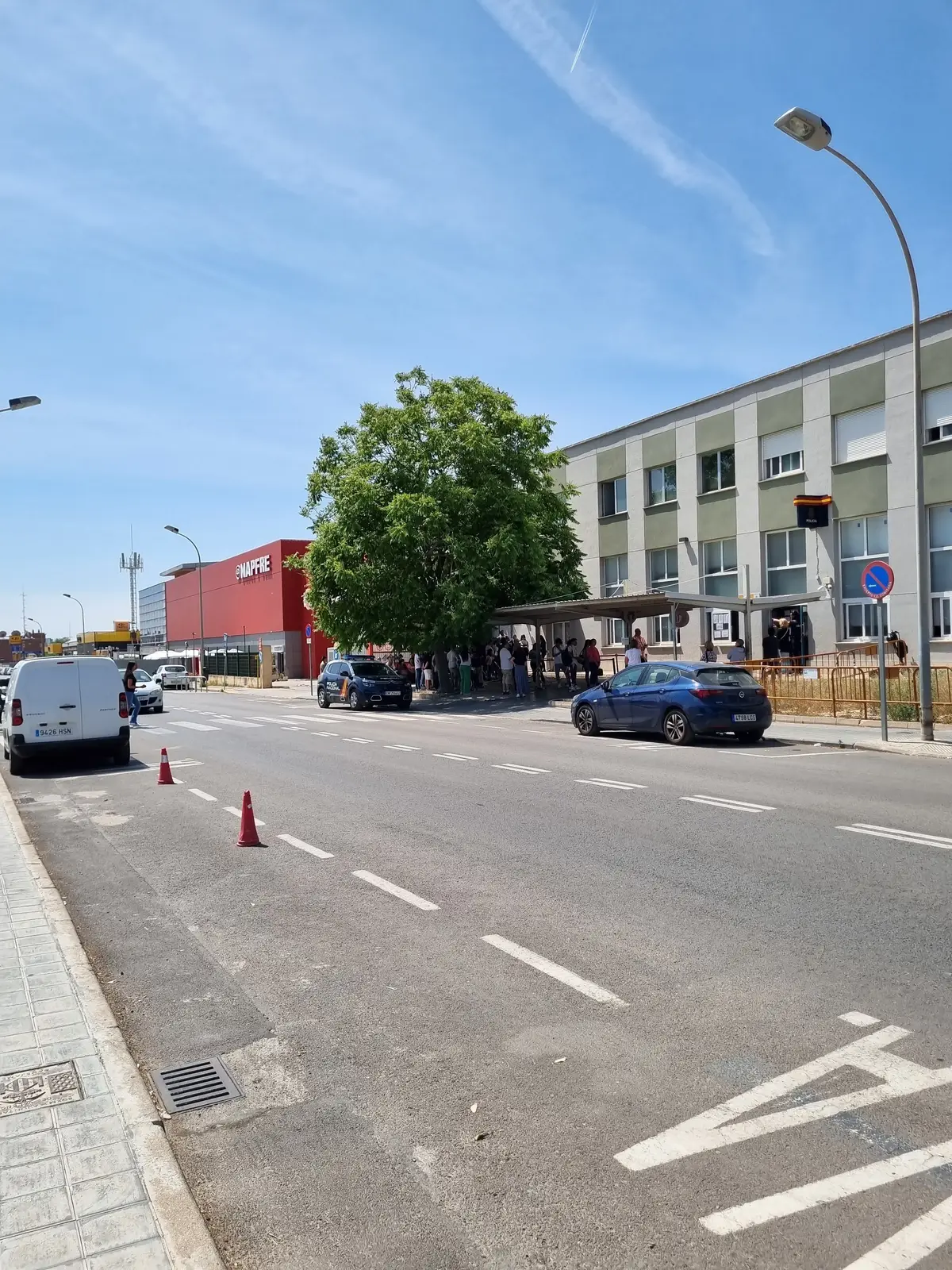 Straße vor der Ausländerstelle der Polizei in Valencia, einige Wartende nahe dem Eingang.
