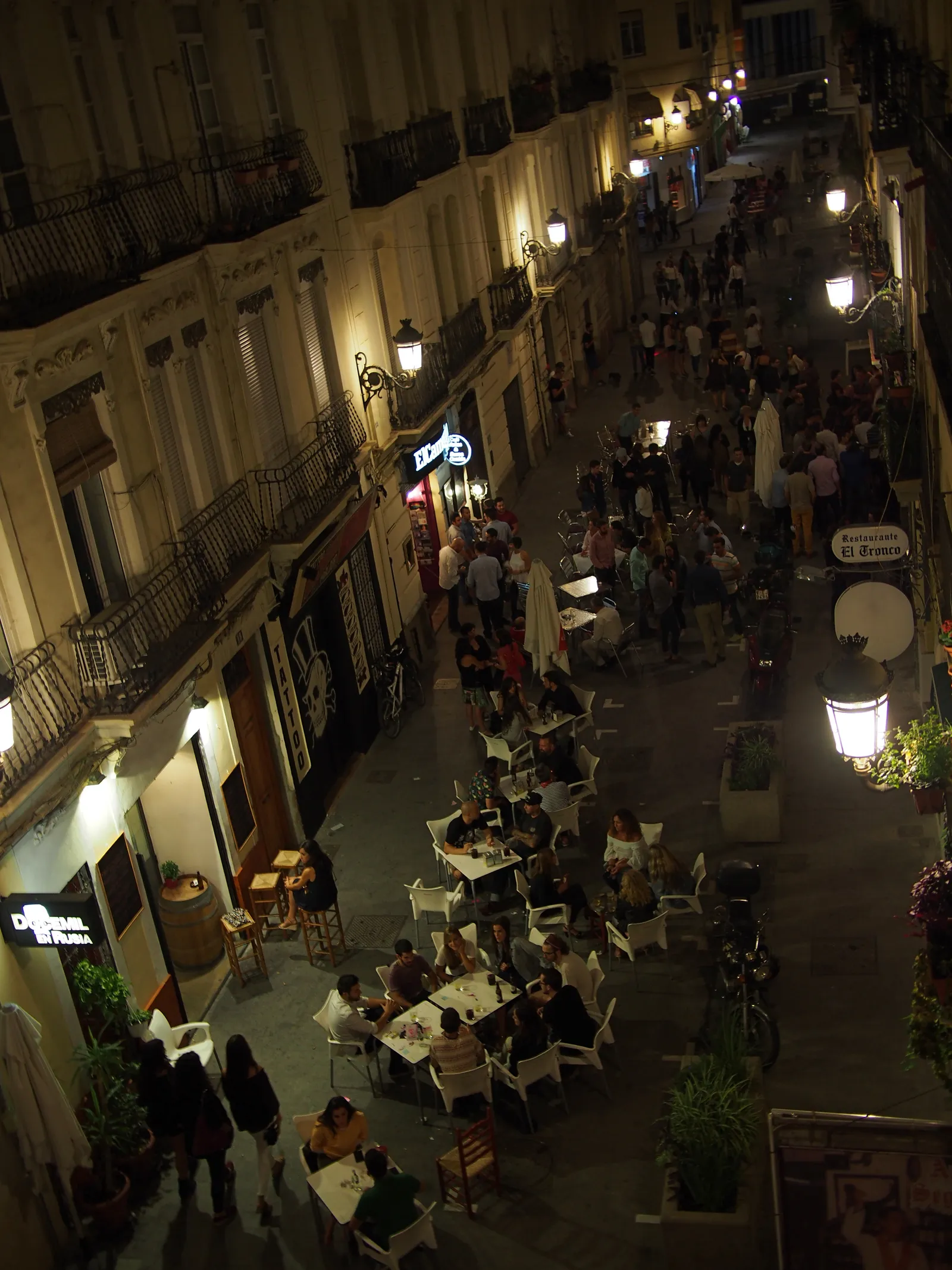 Fußgängerstraße in Russafa bei Nacht von oben gesehen, auf beiden Seiten beleuchtete Restaurantterrassen.