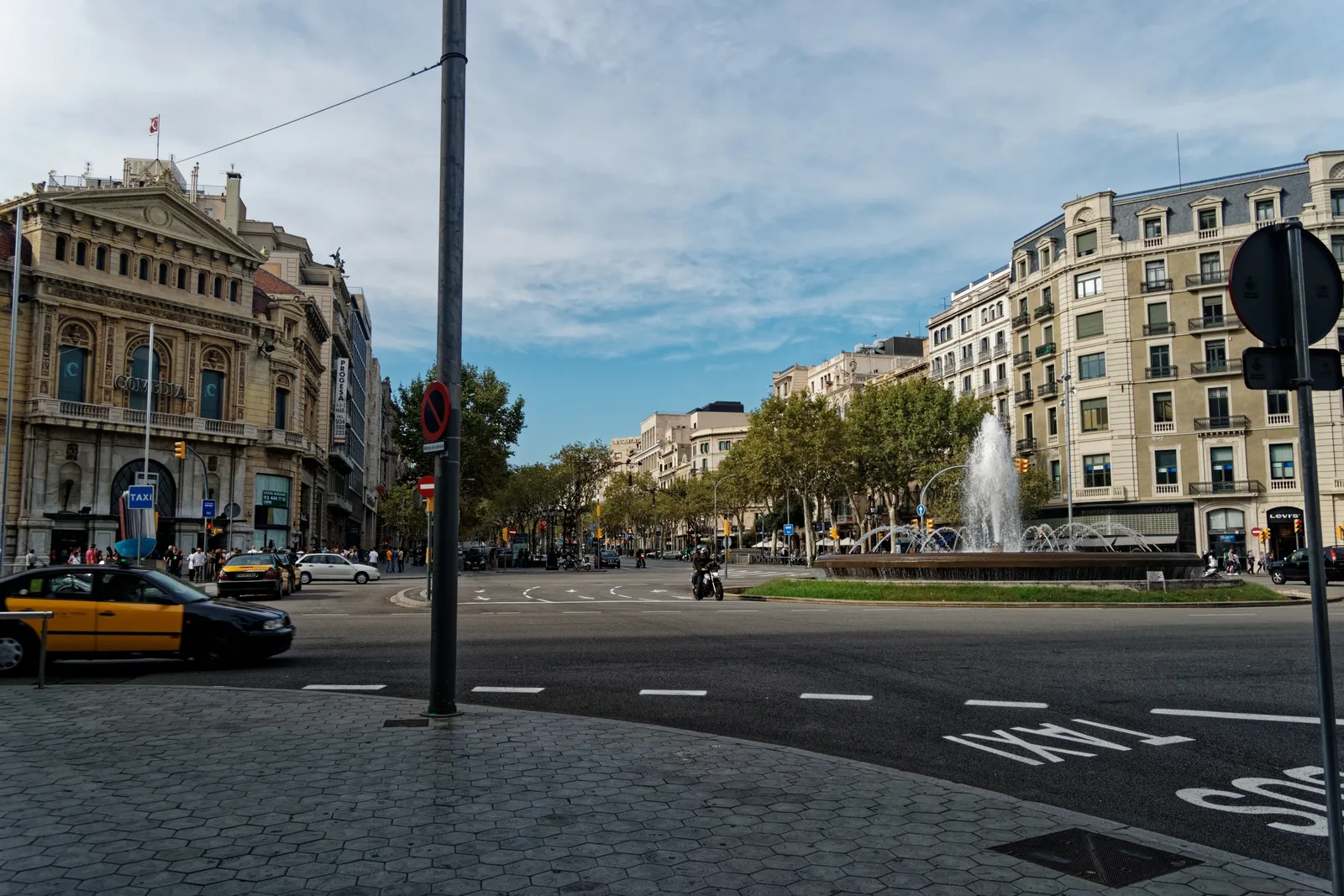 Eine breite Allee in Barcelona mit Brunnen, Taxi und Wohnhäusern aus Stein